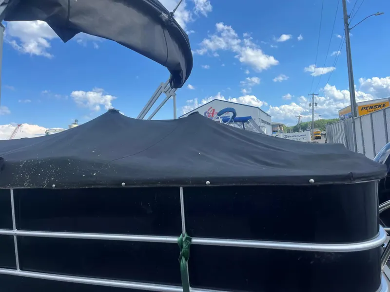 Slide: The Image of A 2015 Sylvan 8522 CNF pontoon boat with a black cover, parked in a storage area. - 21