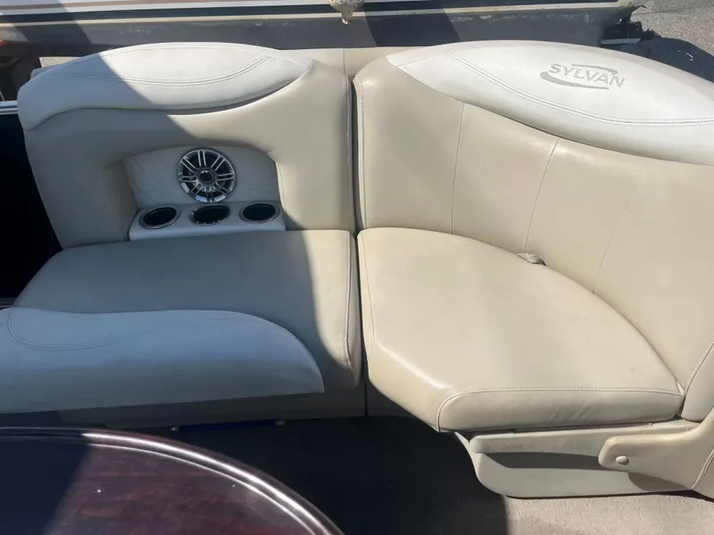 Slide: The Image of The seating area of a 2015 Sylvan 8522 CNF with beige upholstery and cup holders. - 6
