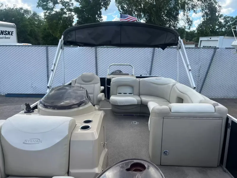 Slide: The Image of The image shows a 2015 Sylvan 8522 CNF pontoon boat with beige seating and a black sunshade. - 7