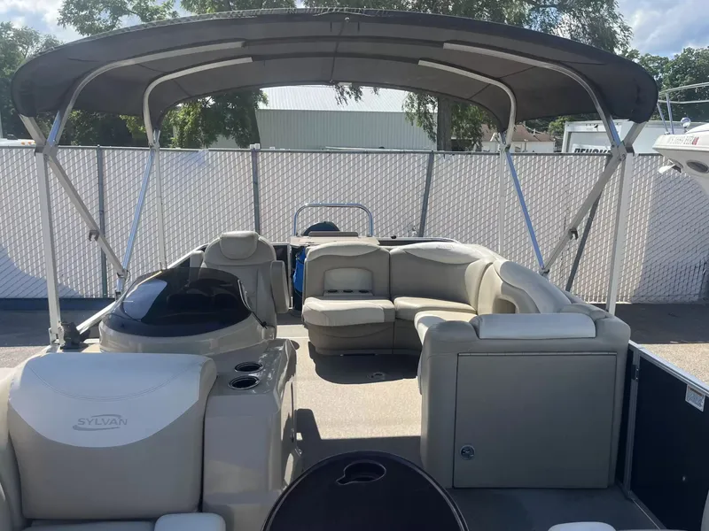 Slide: The Image of The image shows a 2015 Sylvan 8522 CNF pontoon boat with a spacious seating area and a sun canopy. - 8