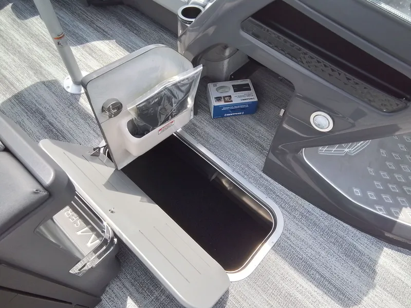 Slide: The Image of The image shows the interior of a Bennington 23M1SB boat with storage space and gray carpeting. - 23