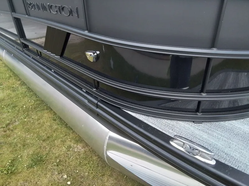 Slide: The Image of Close-up of a Bennington pontoon boat on grass, showing railing and hull details. - 30