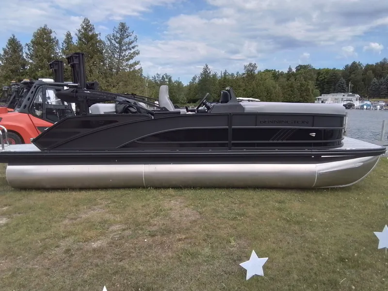 Slide: The Image of A Bennington 23M1SB pontoon boat sits on grass, surrounded by trees and a lake in the background. - 4