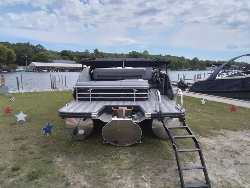 Slide: The Image of 2026 Bennington 23M1SB on shore with ladder and star decorations. - 6