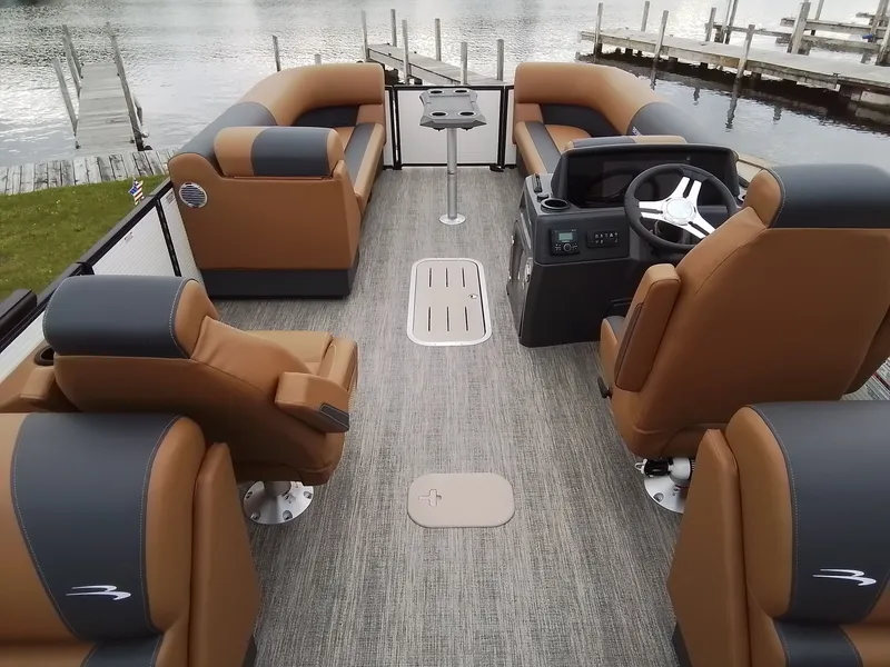 Slide: The Image of Interior of a Bennington 23SSRSF pontoon boat with brown and gray seating, docked by the water. - 10
