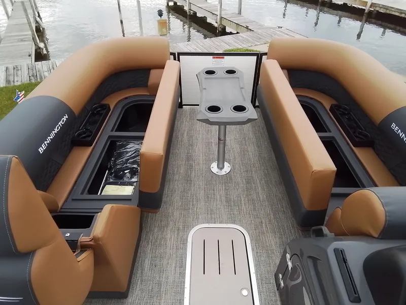 Slide: The Image of Interior of a Bennington 23SSRSF pontoon boat with beige seating and a table with cup holders. - 12