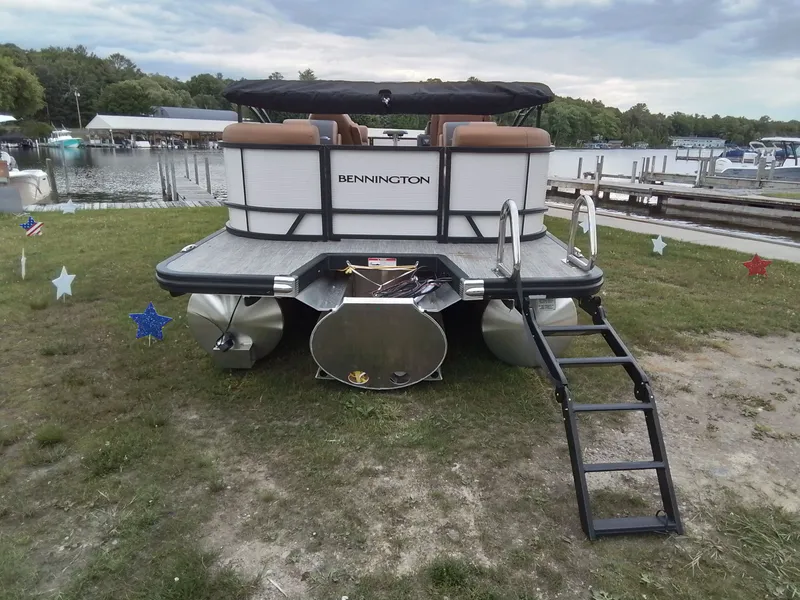 Slide: The Image of A Bennington 23SSRSF pontoon boat is on grass by the shore, with a ladder at the stern. - 5