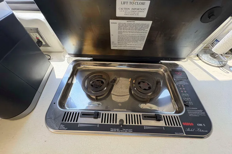 Slide: The Image of 2001 Bayliner 3258 Command Bridge stove with dual burners and safety instructions. - 25