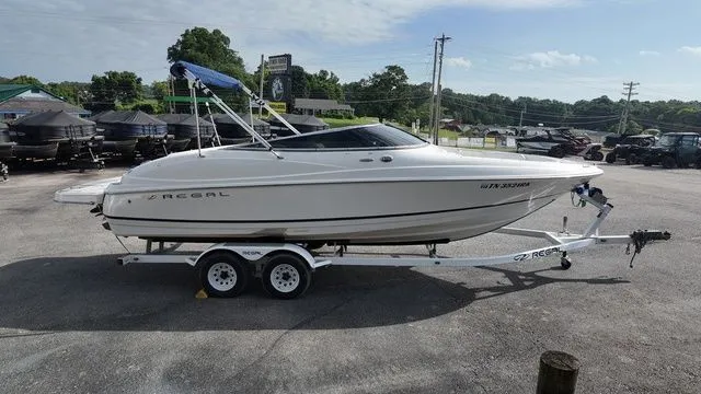 Slide: The Image of A white 2005 Regal 2400 LSR boat is on a trailer in a parking lot. - 6
