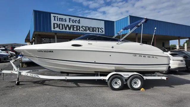Slide: The Image of A white 2005 Regal 2400 LSR boat on a trailer in front of a blue building. - 1