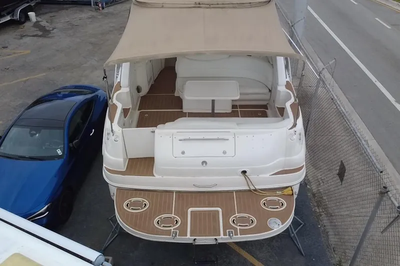 Slide: The Image of 2002 Sea Ray 340 Sundancer boat with canopy, docked beside a blue car. - 12