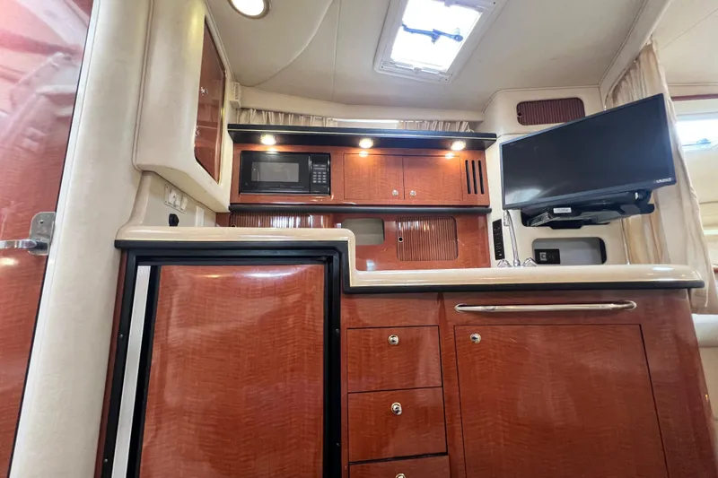 Slide: The Image of 2002 Sea Ray 340 Sundancer interior with wood cabinetry, microwave, and mounted TV. - 34