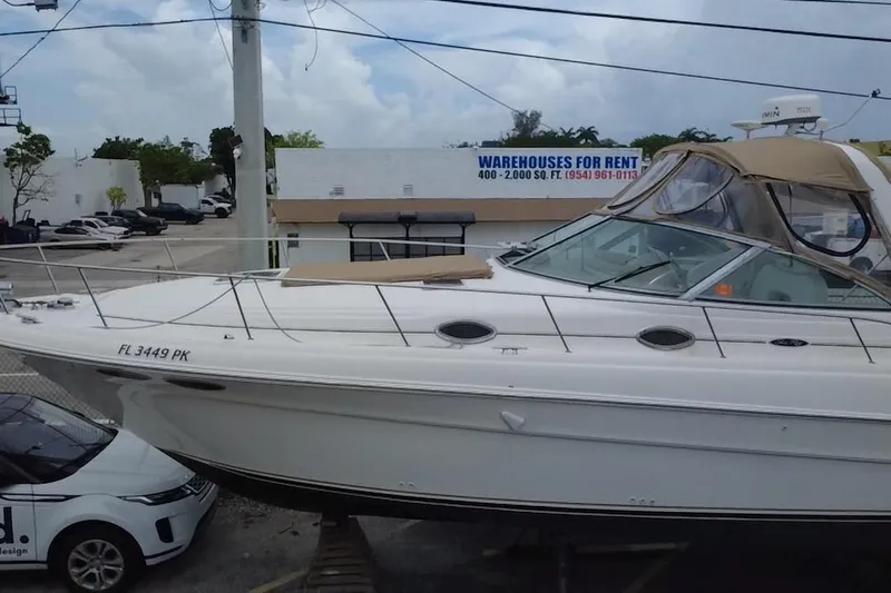 Slide: The Image of 2002 Sea Ray 340 Sundancer yacht docked near rental warehouses, side view. - 6