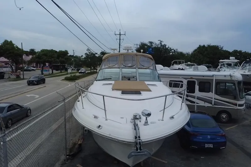 Slide: The Image of 2002 Sea Ray 340 Sundancer yacht parked near road and RV, overcast sky. - 9