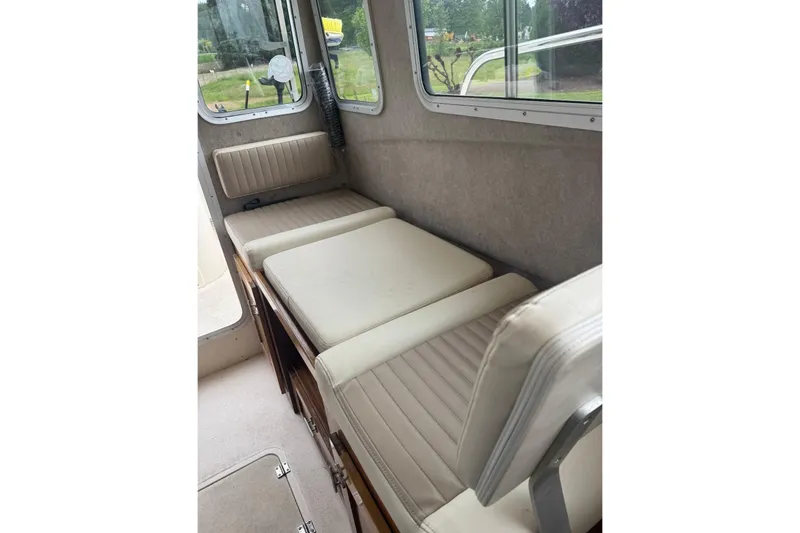 Slide: The Image of Interior seating of 2020 Defiance San Juan 250 boat, featuring cushioned benches and windows. - 11