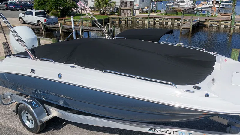 Slide: The Image of A 2027 Stingray 192 SC boat with a black cover on a trailer by the water. - 3