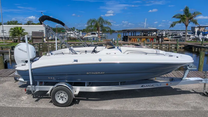 The Image of A modern 2027 Stingray 192 SC on a trailer, featuring a blue hull and bimini top. - 1