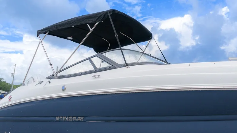 Slide: The Image of A Stingray 211 DC boat with a black canopy against a cloudy sky. - 2