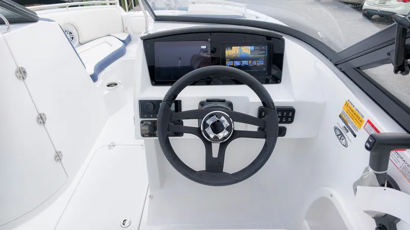 Slide: The Image of The image shows the cockpit of a Stingray 211 DC boat with a modern steering wheel and large display. - 24