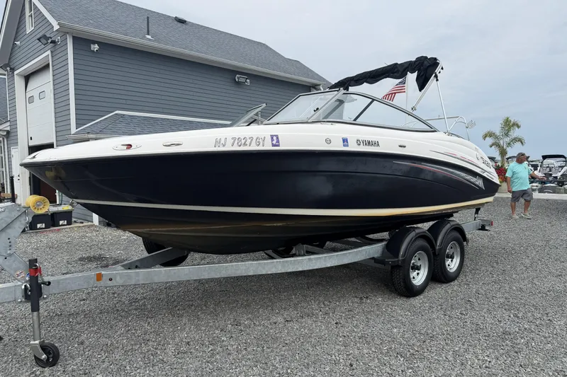 The Image of 2006 Yamaha SX210 boat on trailer, parked near a gray building. - 1