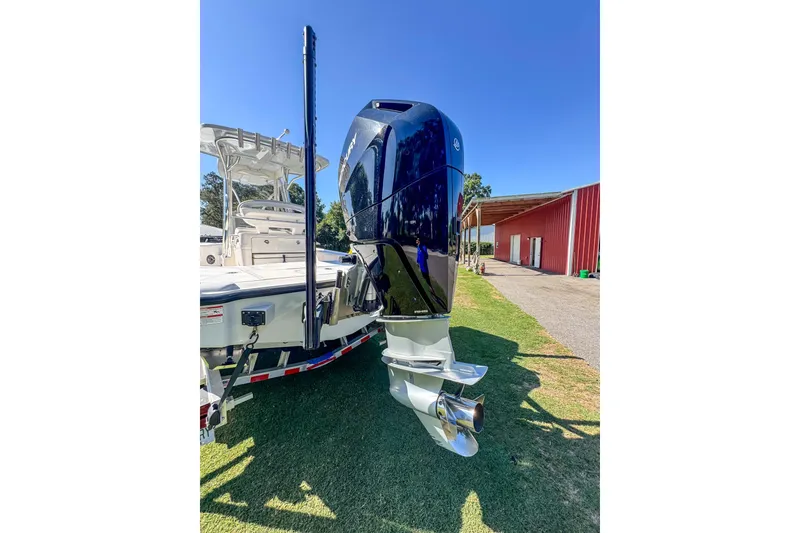 Slide: The Image of 2026 SeaVee 270Z boat with powerful outboard motor, parked on grass under clear blue sky. - 21