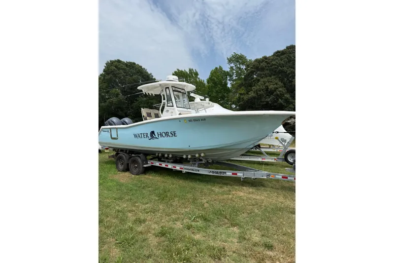 The Image of 2022 Tidewater 272 CC Adventure boat on trailer, labeled "Water Horse," in grassy area. - 1