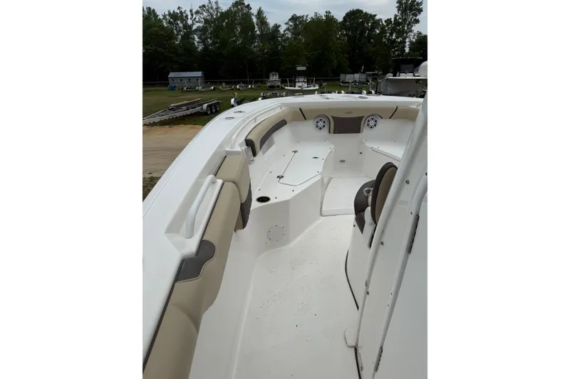 Slide: The Image of 2022 Tidewater 272 CC Adventure boat interior with seating and speakers, surrounded by trees. - 8