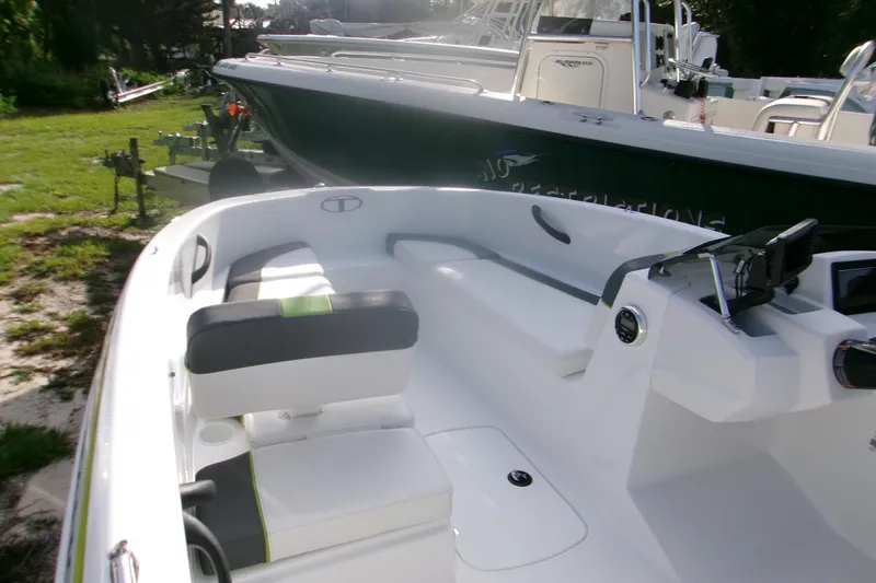 Slide: The Image of 2024 Tahoe T16 boat interior with seating and steering console, parked outdoors. - 5