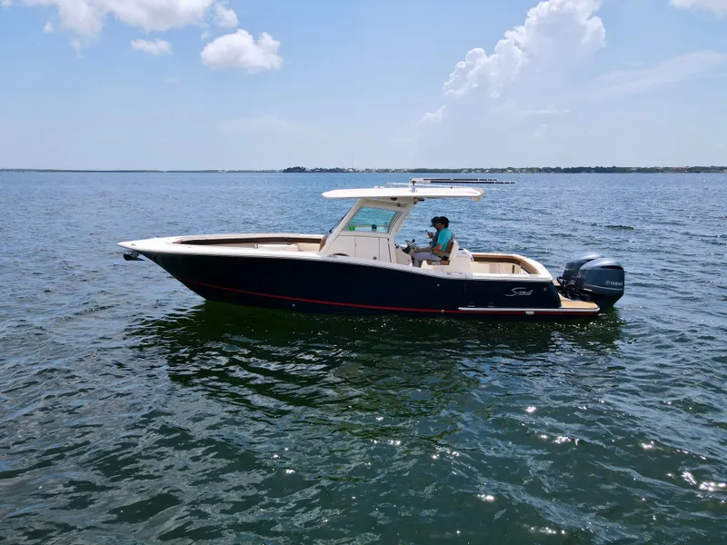 The Image of A 2014 Scout 320 LXF boat cruising on calm water under a blue sky. - 0