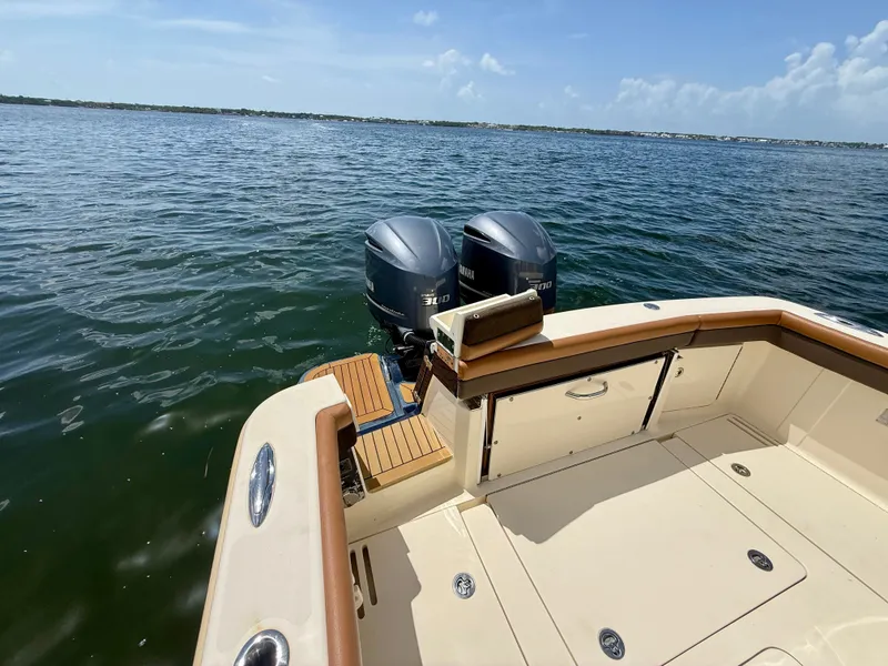 Slide: The Image of A 2014 Scout 320 LXF boat with twin outboard engines on calm water. - 14