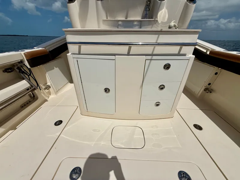 Slide: The Image of The image shows the deck of a 2014 Scout 320 LXF boat with storage and a clear view of the sea. - 18