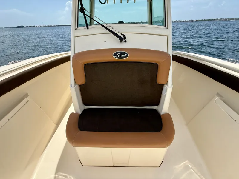 Slide: The Image of A 2014 Scout 320 LXF with a brown bench seat on deck, surrounded by water. - 6