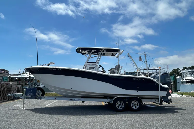 The Image of 2018 Sea Fox 266 Commander boat on trailer, parked near marina under blue sky. - 0