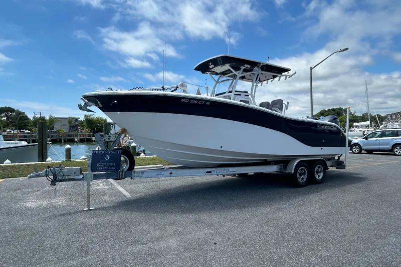 Slide: The Image of 2018 Sea Fox 266 Commander boat on trailer, parked near marina under blue sky. - 1