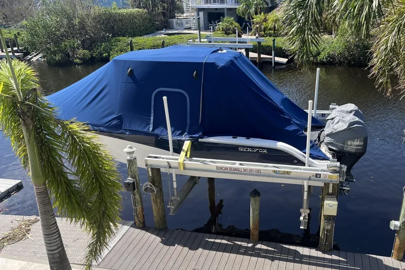 Slide: The Image of 2018 Sea Fox 266 Commander boat covered and docked on a lift by the water. - 29