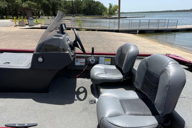 Slide: The Image of 2019 Tracker Pro 160 boat interior with two seats near a lakeside dock. - 23