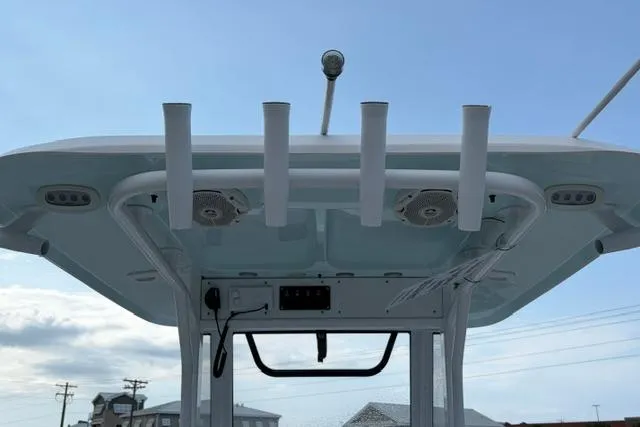 Slide: The Image of 2018 Sea Hunt Ultra 255 SE boat top with rod holders and speakers against blue sky. - 8