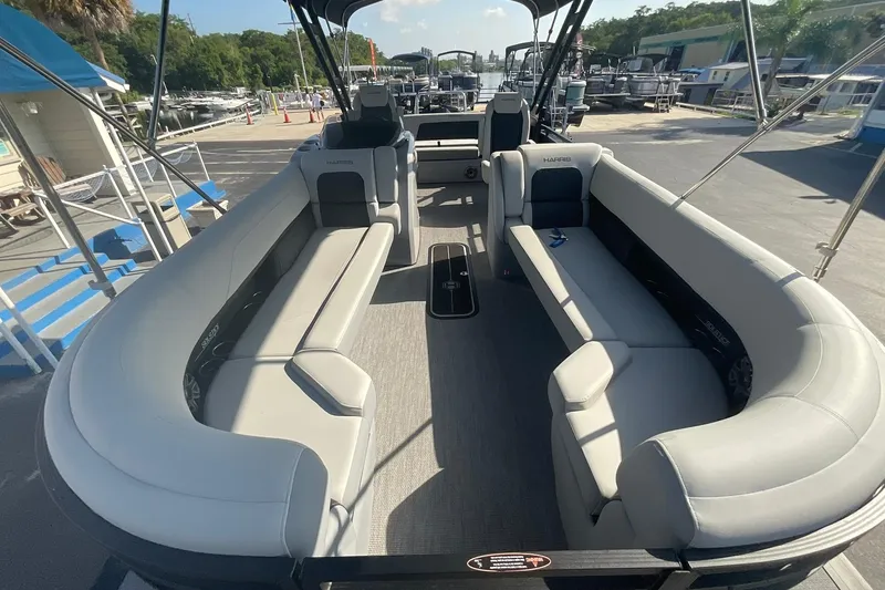 Slide: The Image of 2025 Harris Solstice 250 SLEC pontoon boat with spacious seating at a marina. - 12