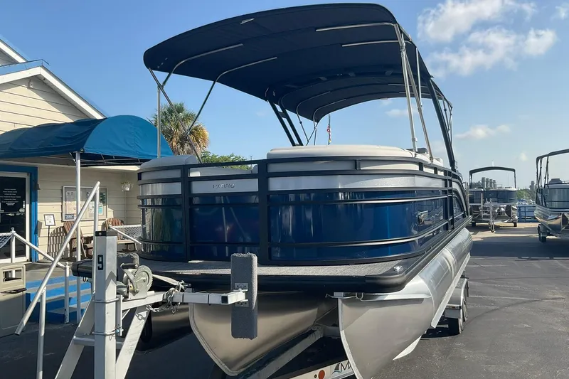 Slide: The Image of 2025 Harris Solstice 250 SLEC pontoon boat on trailer, parked outdoors under blue sky. - 3