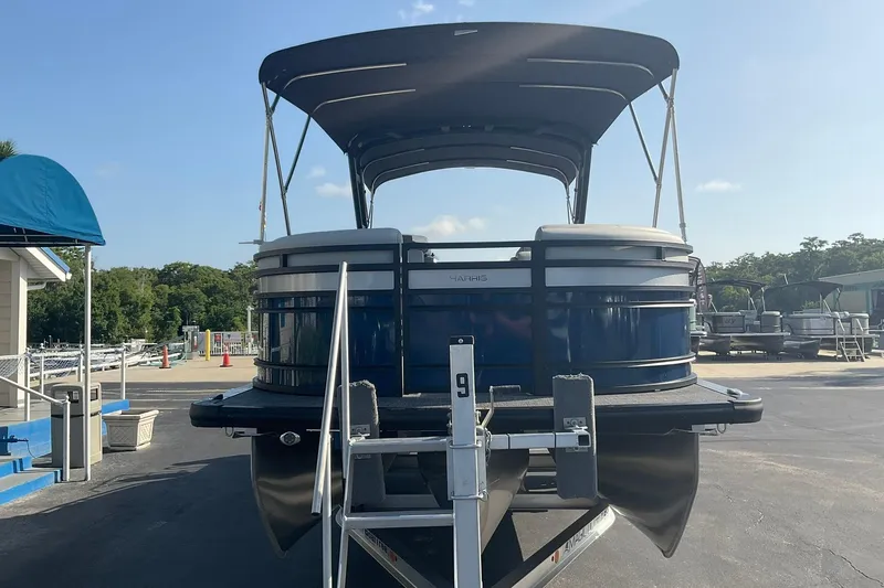 Slide: The Image of 2025 Harris Solstice 250 SLEC pontoon boat with canopy, parked on a trailer. - 4