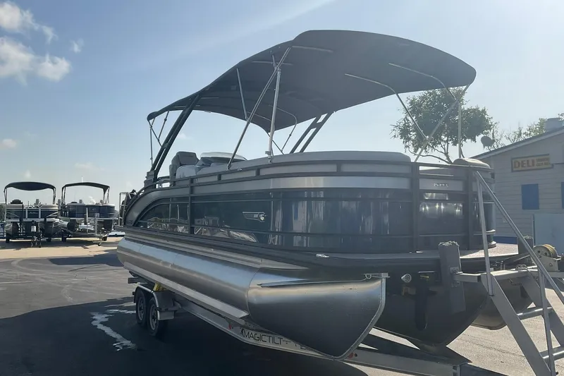 Slide: The Image of 2025 Harris Solstice 250 SLEC pontoon boat on trailer, parked outdoors under clear sky. - 5