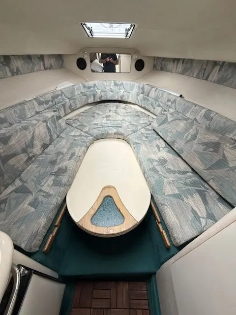 Slide: The Image of Interior of a 1994 Sea Ray 270 with cushioned seating areas and a table. - 14