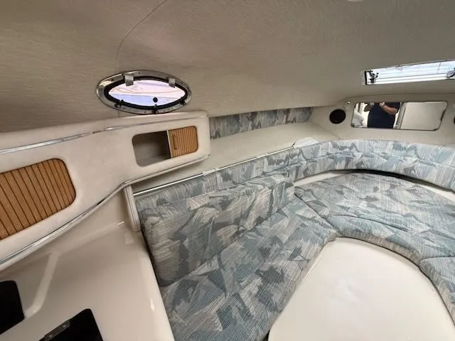 Slide: The Image of Interior of a 1994 Sea Ray 270 with cushioned seating and a porthole. - 15