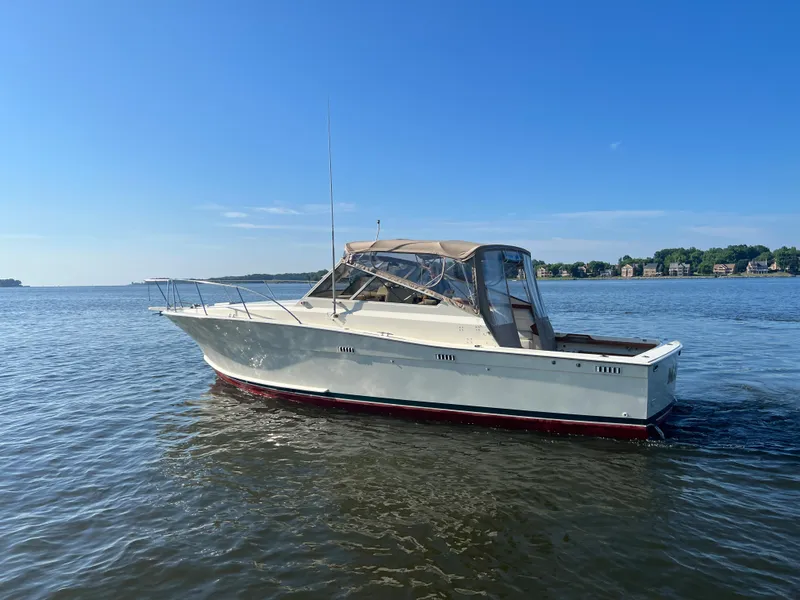 Slide: The Image of Ein weißes Boot mit rotem Unterboden fährt auf ruhigem Wasser unter blauem Himmel. - 9
