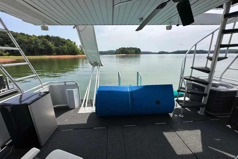 Slide: The Image of Houseboat deck view with spiral staircase, overlooking serene lake and lush green shoreline. - 20