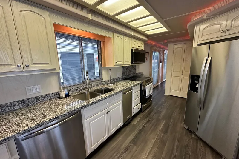 Slide: The Image of Modern kitchen with granite countertops, stainless steel appliances, and wood flooring in a Fantasy 18x82 model. - 6