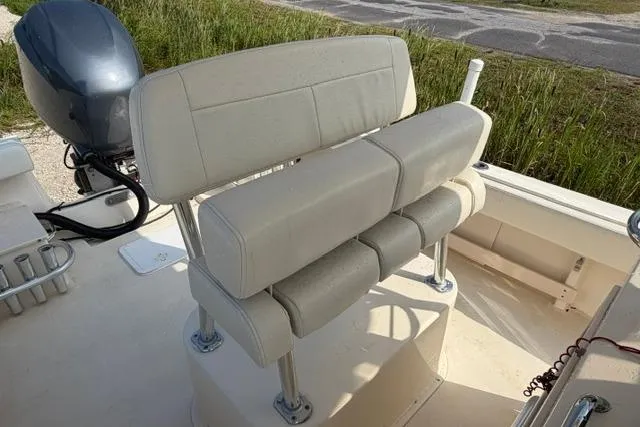 Slide: The Image of 2007 Parker 23 SE boat with cushioned seating and outboard motor, parked near grassy area. - 10