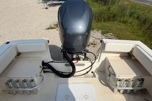 Slide: The Image of 2007 Parker 23 SE boat with outboard motor and rod holders, parked on gravel. - 8