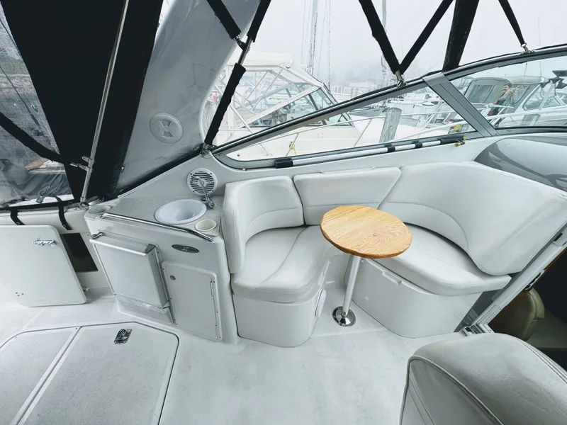 Slide: The Image of Interior of a 2001 Four Winns 298 Vista with white upholstery and a round wooden table. - 12