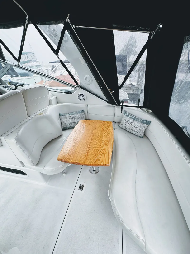 Slide: The Image of Interior of a 2001 Four Winns 298 Vista with white upholstery and a wooden table. - 14